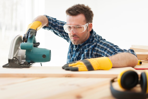 Free photo focused carpenter cutting wooden plank