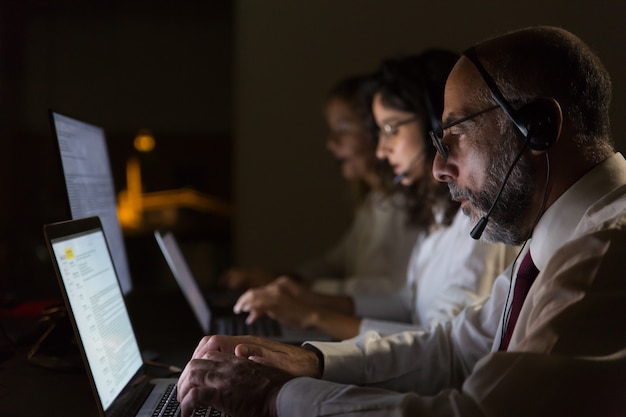 Free Photo focused coworkers in headsets typing on laptops