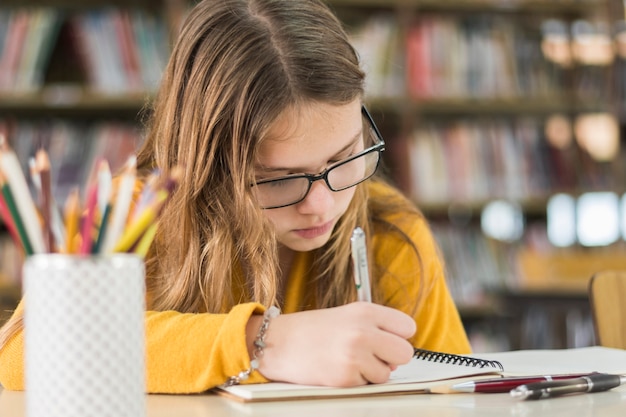 Free photo focused girl doing homework in library