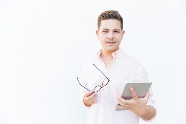 Free photo focused guy holding eyeglasses and tablet