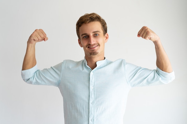 Free photo focused guy in white casual shirt showing strength gesture.