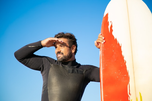 Free photo focused handsome surfer staring into distance