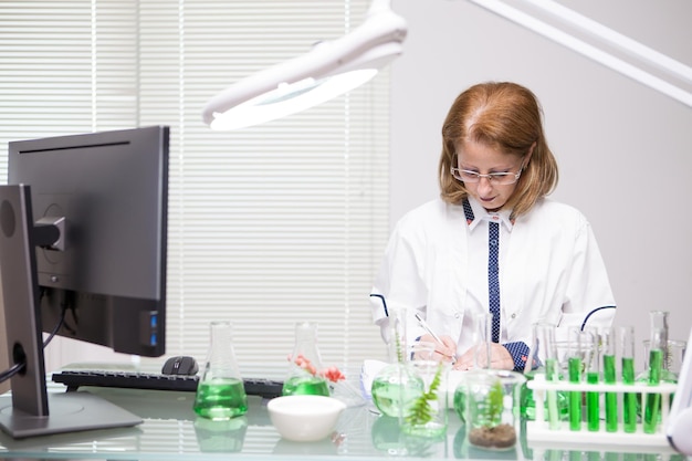 Free Photo focused middle age woman taking notes after scientific test in a production laboratory. biologist working.