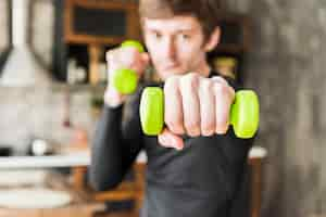 Free photo focused sportsman training with small dumbbells