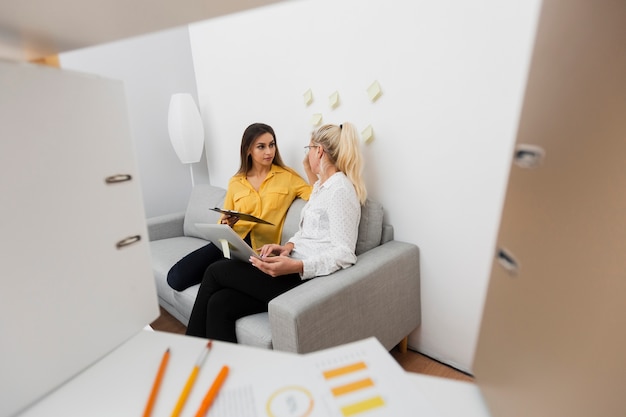 Free Photo focused woman talking with her colleague on sofa