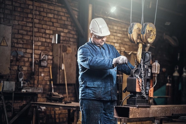 Free photo focused worker is using a small mobile drill to make a holes in the part of rail.