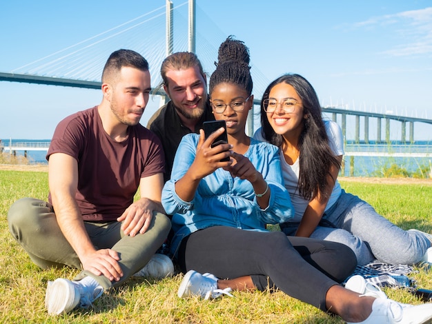 Focused young friends using smartphone outdoor