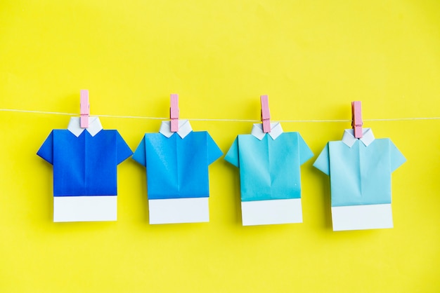 Free photo folded paper shirts hanging on clothes line