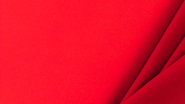 Folded red textile fabric on colored background