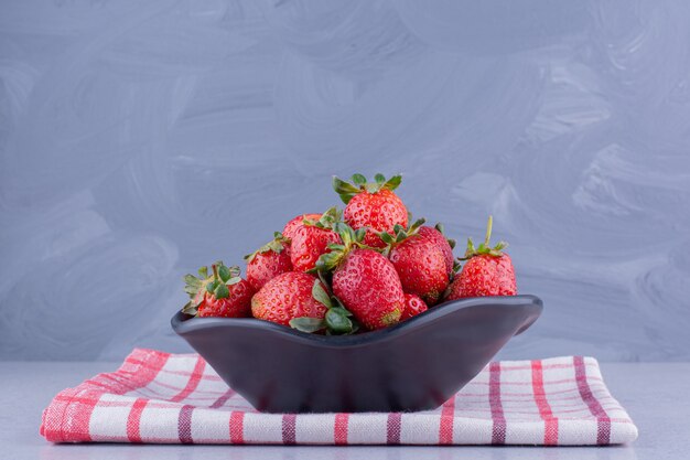 Free Photo folded towel under a bowl with a heap of strawberries on marble background. high quality photo