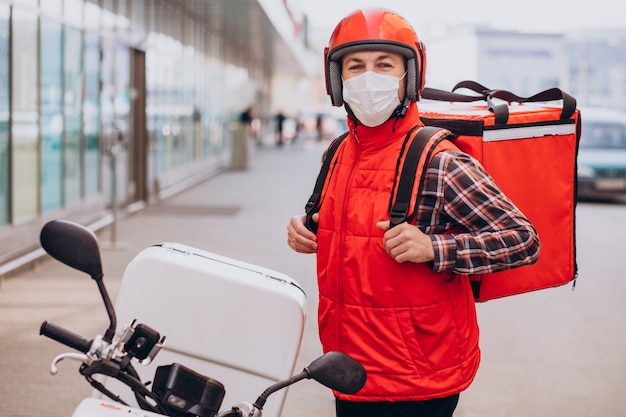 Free photo food delivery boy driving scooter with box with food and wearing mask