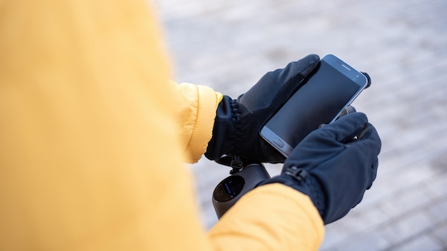 Free photo food delivery man on a scooter using his smartphone. yellow jacket and black gloves. winter