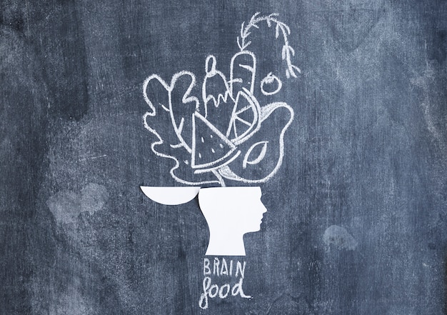 Free photo food drawn over the open head paper cutout with text on chalkboard