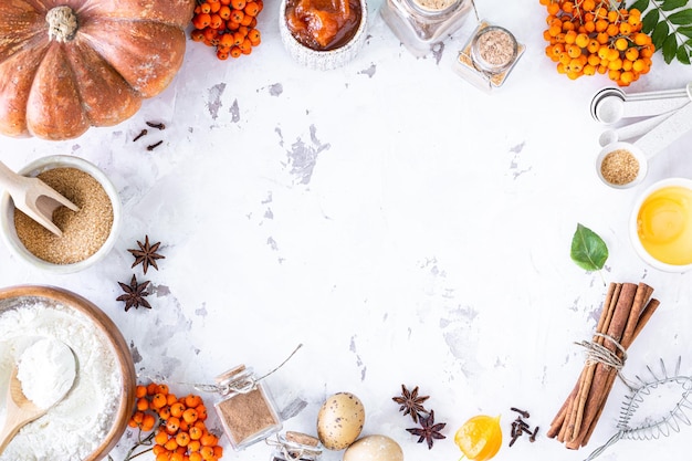 Food ingredients for making autumn pumpkin pie on white stone background Homemade baking concept Top view Copy space