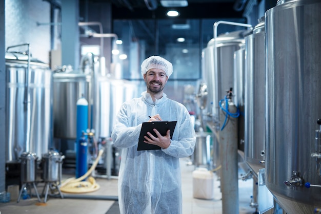 Free photo food processing plant interior with positive smiling technologist holding checklist