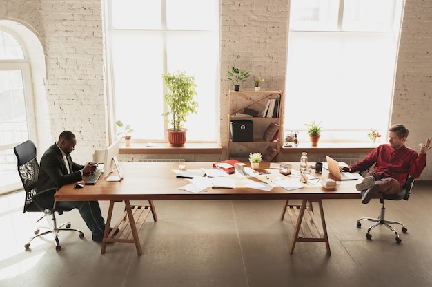 Free photo fools around in front of his boss. caucasian worker, manager trying to work in office.