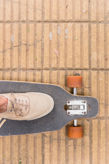 Free photo foot in sneakers standing on longboard