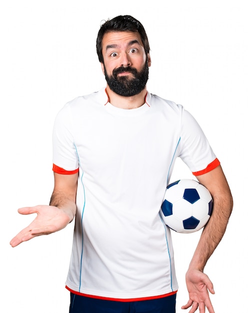 Free photo football player holding a soccer ball making unimportant gesture