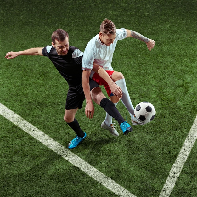 Football player tackling for ball over green grass background.