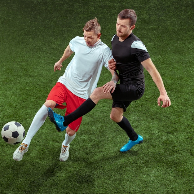 Free photo football player tackling for ball over green grass background.