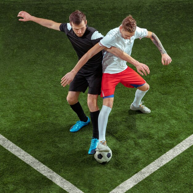 Football player tackling for ball over green grass background.