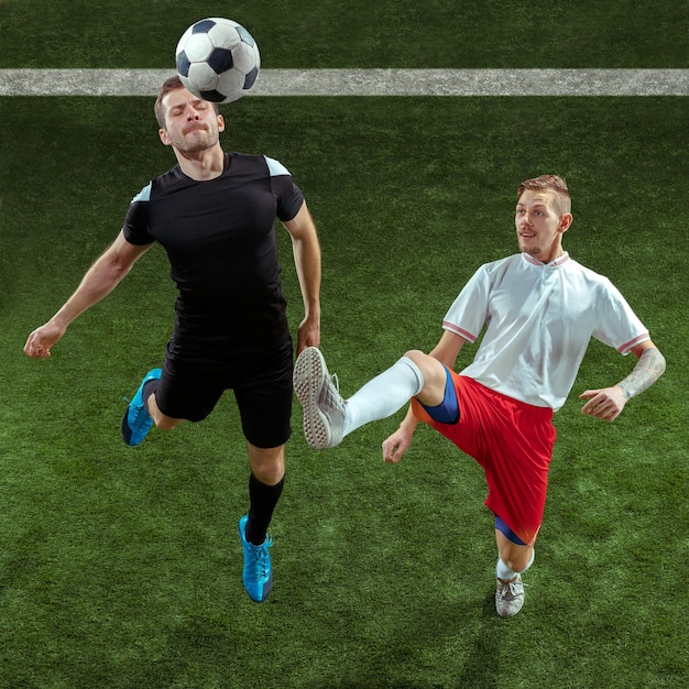 Free photo football player tackling for ball over green grass background.