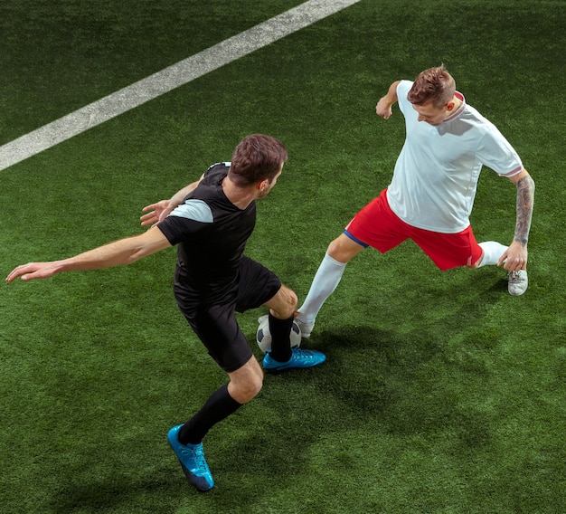 Football player tackling for ball over green grass