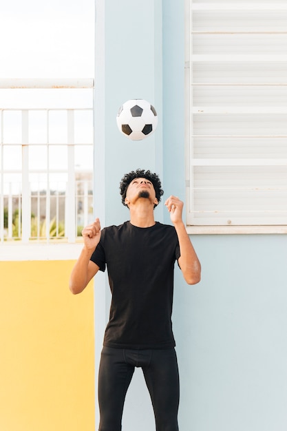 Free photo football player throwing up ball at porch