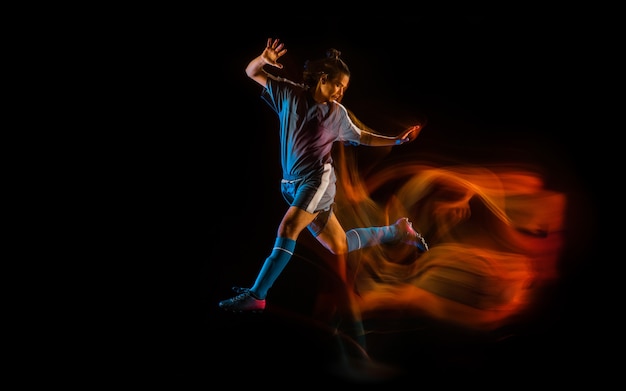 Football or soccer player on black background in mixed light fire shadows