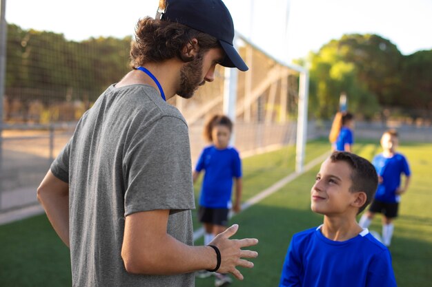 Football trainer helping kids medium shot