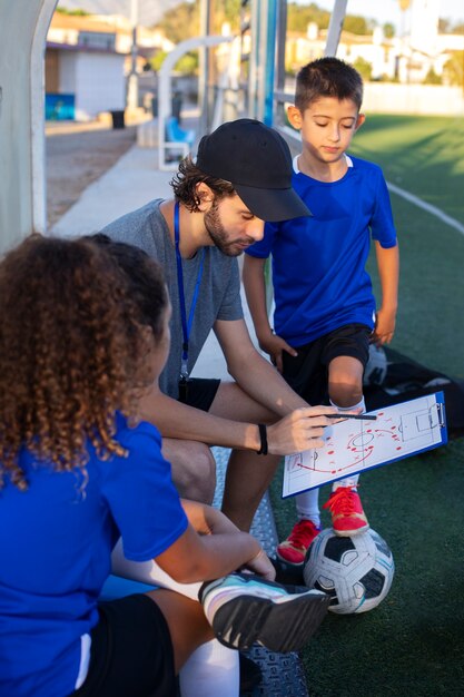 Football trainer teaching kids  side view