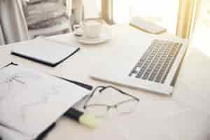 Free photo foreground of objects on the working place: eyeglasses, diagrammes, laptop, notebook