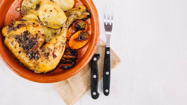 Fork and knife near delicious chicken leg