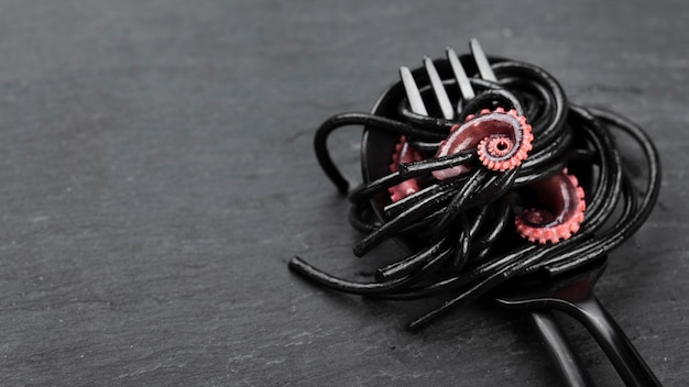 Free photo fork with black pasta and squid