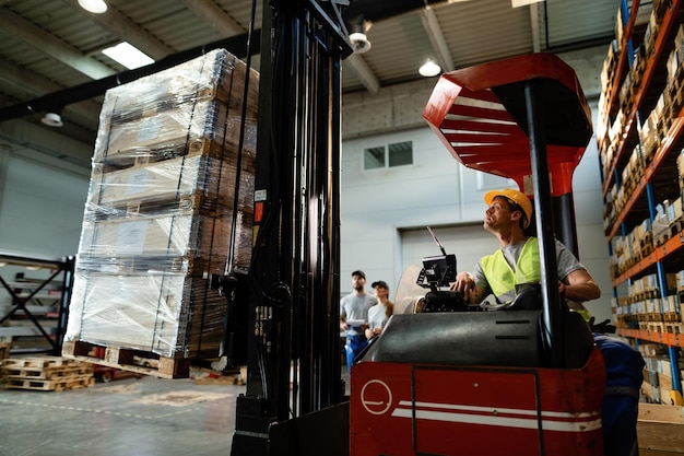 Free photo forklift operator loading cargo while working in a warehouse his colleagues are in the background