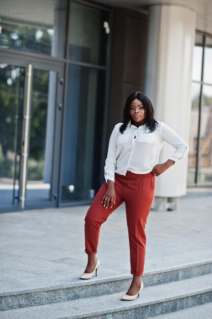 Formally dressed african american business woman in white blouse and red trousers Successful dark skinned businesswoman