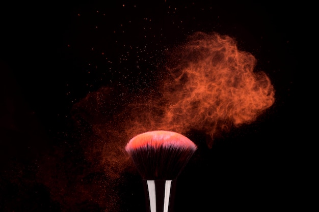 Free photo foundation brush with flying particles of bright powder