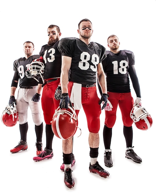 Free photo the four caucasian fitness men as american football players posing  full-length with a ball on white background