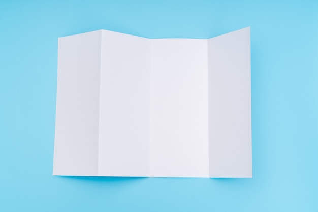 Free Photo four- fold white template paper on blue background .