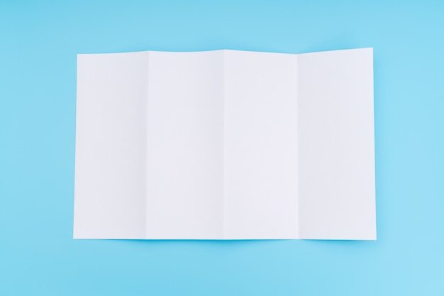 Free photo four- fold white template paper on blue background .