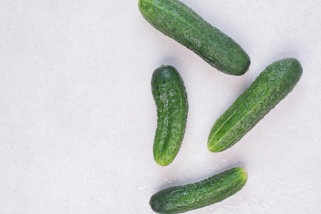 Four fresh cucumbers on white table.