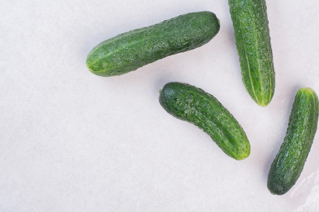 Four fresh cucumbers on white table.