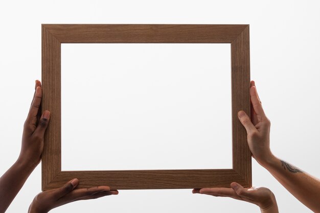 Free Photo four hands holding big wooden frame