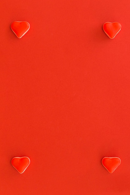 Free photo four heart shape candies at the corner of red background