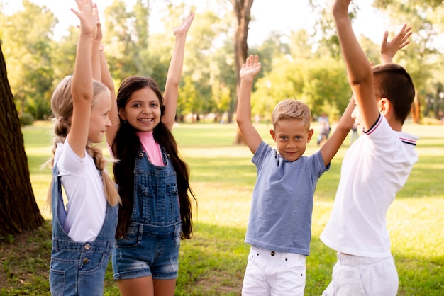 Four joyful friends raising hands up