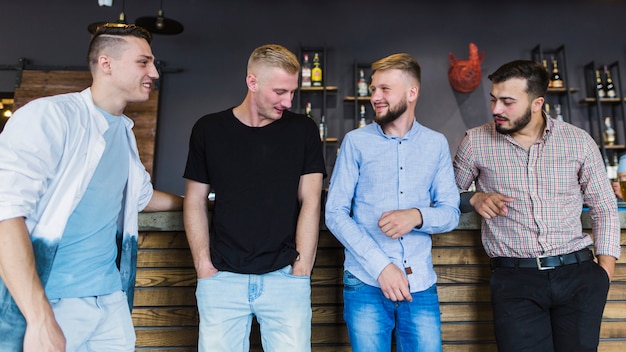 Free photo four male friends in casual wear standing at bar counter