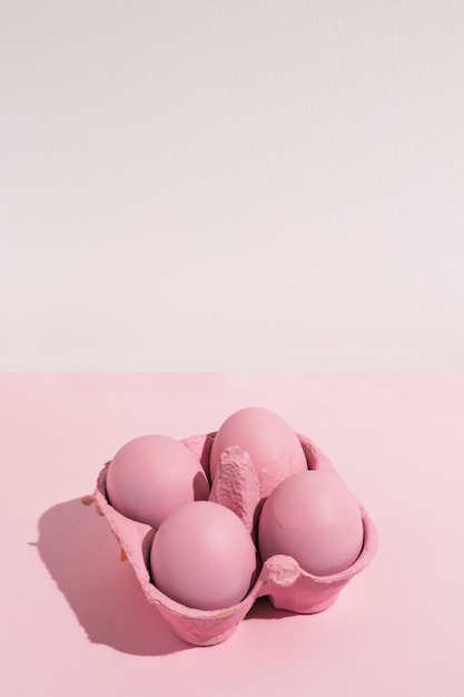 Free photo four pink easter eggs in rack on light table