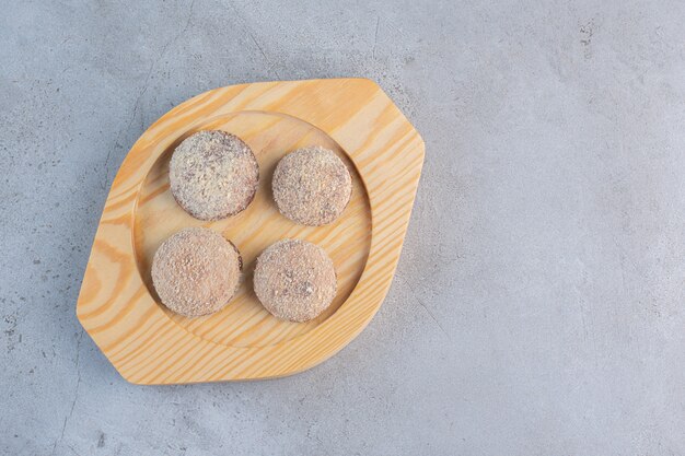 Four tasty truffle balls placed on wooden plate.