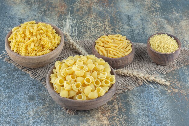 Four types of pasta in bowls, on the marble surface.