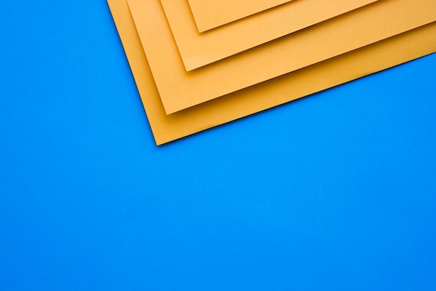 Four yellow cardboard papers on blue surface